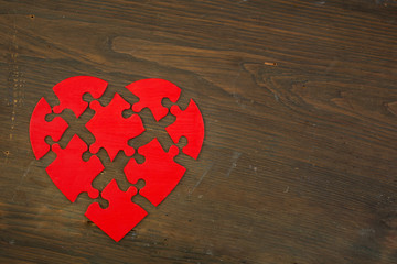Exploding red heart puzzle on wooden table