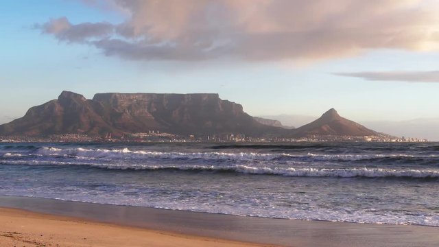 Table Mountain, Devils Peak and Lions Head Mountains in Cape Town, South Africa with sand and sea in the foreground.