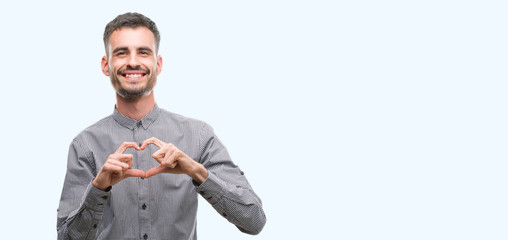 Young hipster man smiling in love showing heart symbol and shape with hands. Romantic concept.