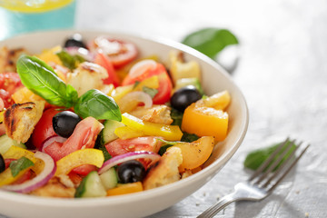Panzanella salad with heirloom tomatoes and ciabatta in ceramic bowl on the kitchen table.