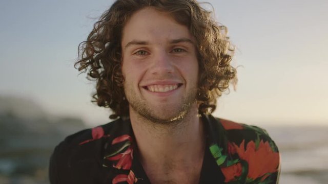 close up portrait of attractive young man smiling cheerful  wearing aloha shirt at sunset
