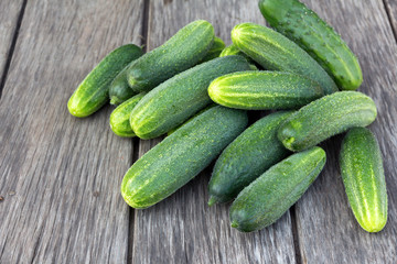 a lot of fresh green cucumbers on a board rustic table
