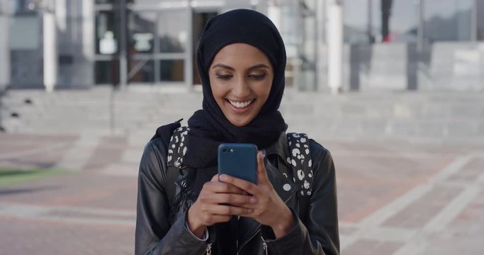 portrait beautiful young muslim woman using smartphone video chatting enjoying talking on mobile phone smiling excited ethnic female wearing hijab in city slow motion
