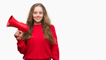 Young blonde woman holding red megaphone with a happy face standing and smiling with a confident smile showing teeth