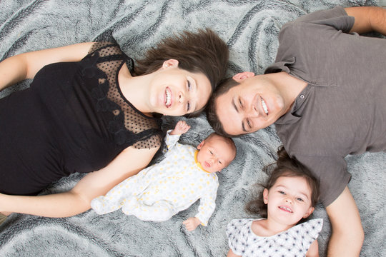 top view of Happy Young Family of four lying on home house floor