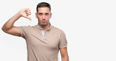 Handsome young man with angry face, negative sign showing dislike with thumbs down, rejection concept