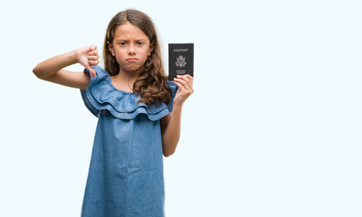 Brunette hispanic girl holding passport of United States of America with angry face, negative sign showing dislike with thumbs down, rejection concept