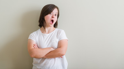 Down syndrome woman standing over wall afraid and shocked with surprise expression, fear and excited face.