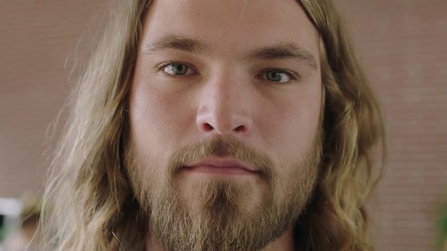 close up portrait of attractive young blonde man looking serious pensive at camera long hair beard