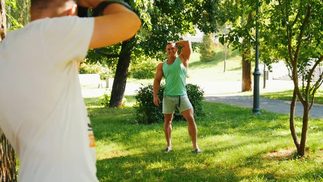 Muscular handsome body-builder posing to photographer in the park