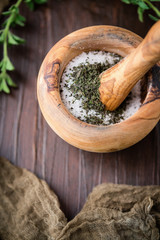 Dried Oregano in Mortar and Pestle to make Herb Salt with a fresh sprig of Oregano on a Wooden Table