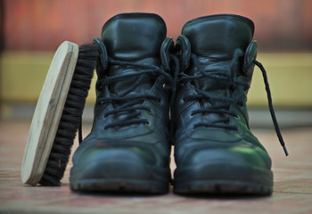 A pair of men black shoes on ceramic tiles in front of door