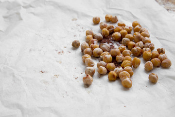 Roasted chickpeas with spices on paper, side view. Copy space.