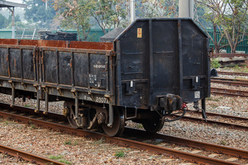 Plakat Empty old rusted cargo train at the train station in Taiwan. Railroad tracks, rusted metal, goods transportation. Rusted wheels, open top with folding doors on the outside to load cargo.