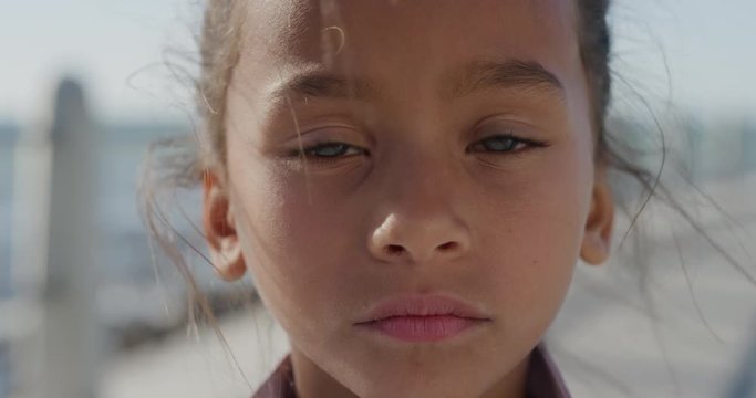 close up portrait young little mixed race girl looking serious contemplative kid on sunny seaside beach slow motion