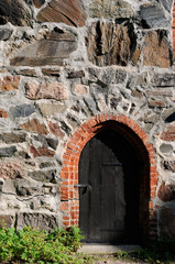 Old dark wooden door in medieval castle stone wall.