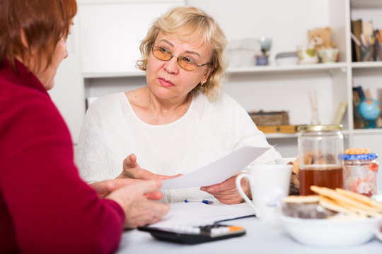 Upset mature woman talking with female about papers