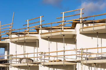 Detail of a house construction with concrete walls, balconies and scaffolding.