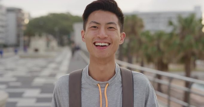 Portrait Happy Young Asian Man Tourist Laughing Enjoying Summer Vacation Independent Teenage Male Looking Cheerful On Urban Waterfront At Sunset Real People Series