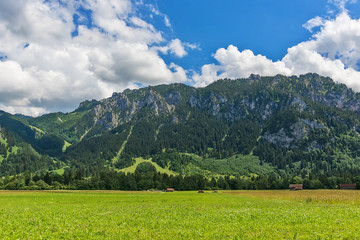 Fototapeta premium Idyllic landscape in the Alps with green meadows and clouds