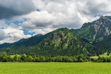Fototapeta premium Idyllic landscape in the Alps with green meadows and clouds