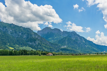 Fototapeta premium Idyllic landscape in the Alps with green meadows and clouds