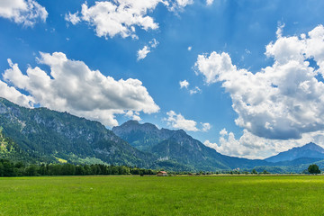 Idyllic landscape in the Alps with green meadows and clouds