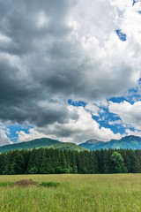 Fototapeta premium Idyllic landscape in the Alps with green meadows and clouds