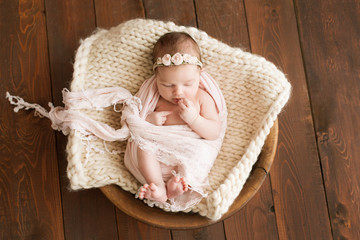 Newborn girl on a brown background. Photoshoot for the newborn. 7 days from birth. A portrait of a...