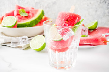 Sweet summer watermelon and lime popsicles with sliced watermelon and mint, on white marble background copy space