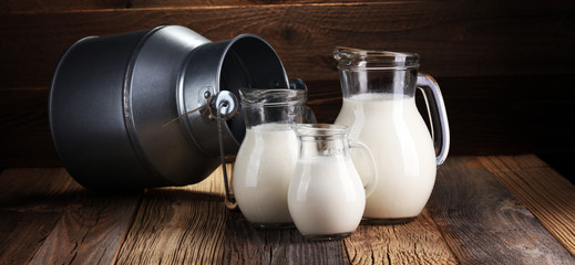 A jug of milk and glass of milk on a wooden table