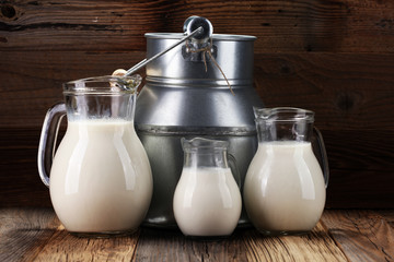 A jug of milk and glass of milk on a wooden table