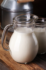 Obraz na płótnie Canvas A jug of milk and glass of milk on a wooden table