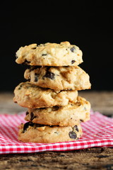 Pile of chocolate chip cookies on napkin with dark background.