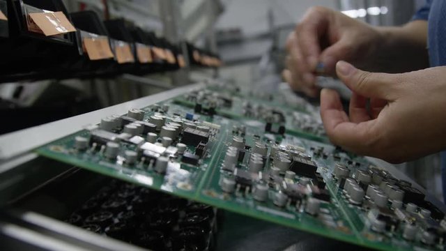 Circuit board manufacturing in a high tech electronics factory close up macro. Female hands building the internal boards for consumer electronics