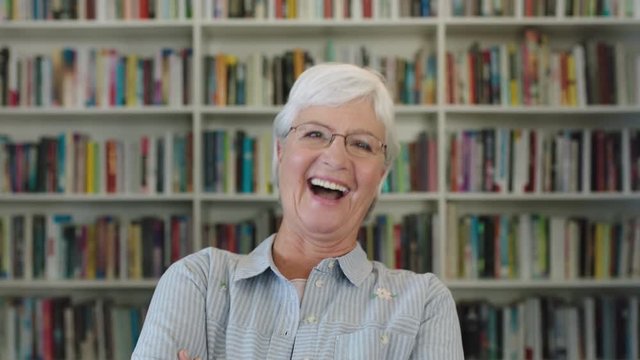 portrait of elegant middle aged woman teacher laughing cheerful looking at camera excited elderly lady wearing glasses in library