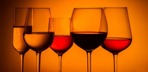 Set of wine glasses with red, white and rose wine on orange background, banner