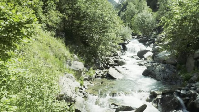 Woman Hiker sitting on the edge of a river flowing through Auron, France.