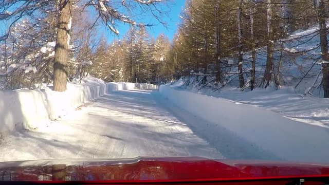 Red car POV driving in snow street in the woods. Shot taken in Bardonecchia, Italy