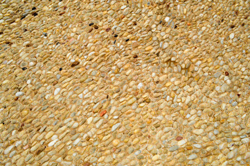 Texture of a stone wall, roads from small round and oval stones with sand with seams of natural old yellow black brown. The background