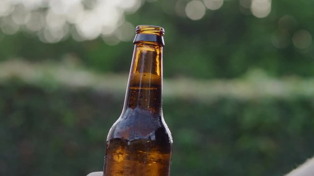 SLOW MOTION lowering brown opened beer bottle