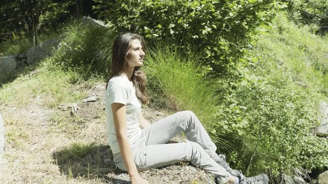 Woman Hiker sitting on the edge of a river flowing through Auron, France.