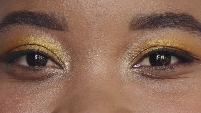 close up african american woman eyes wearing makeup looking happy at camera blinking beauty cosmetics