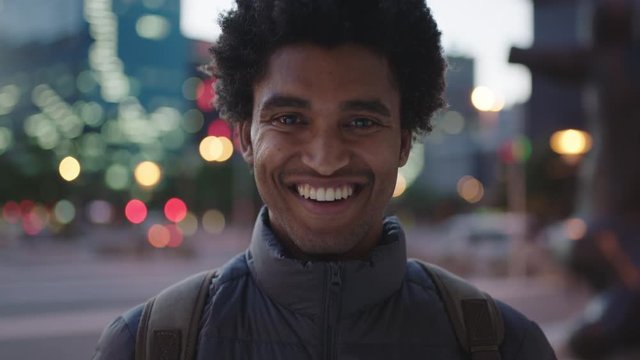close up portrait of attractive young mixed race man smiling cheerful at camera enjoying calm urban evening in city commuting travel