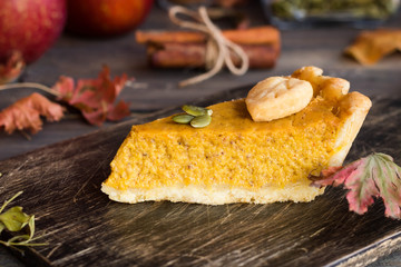 Traditional homemade American pumpkin pie with a decor of leaves and pumpkin seeds for a holiday