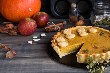 Traditional homemade American pumpkin pie with a decor of leaves and pumpkin seeds for a holiday