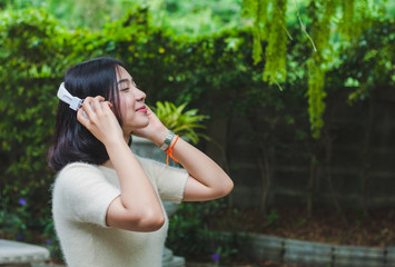 Naklejka premium Beautiful Asian girl listening to music in the garden.