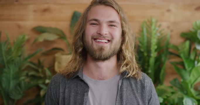 portrait of handsome young man smiling happy enjoying successful lifestyle blonde caucasian male with long hair slow motion