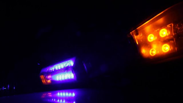 Luces Intermitentes de advertencia lanzando flash de colores en coche de la policia por la noche