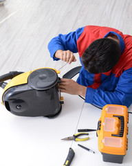 Man repairman repairing vacuum cleaner at service center